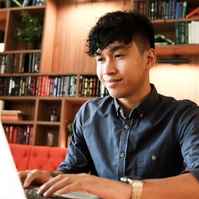 Young man in a home office setting working on a laptop